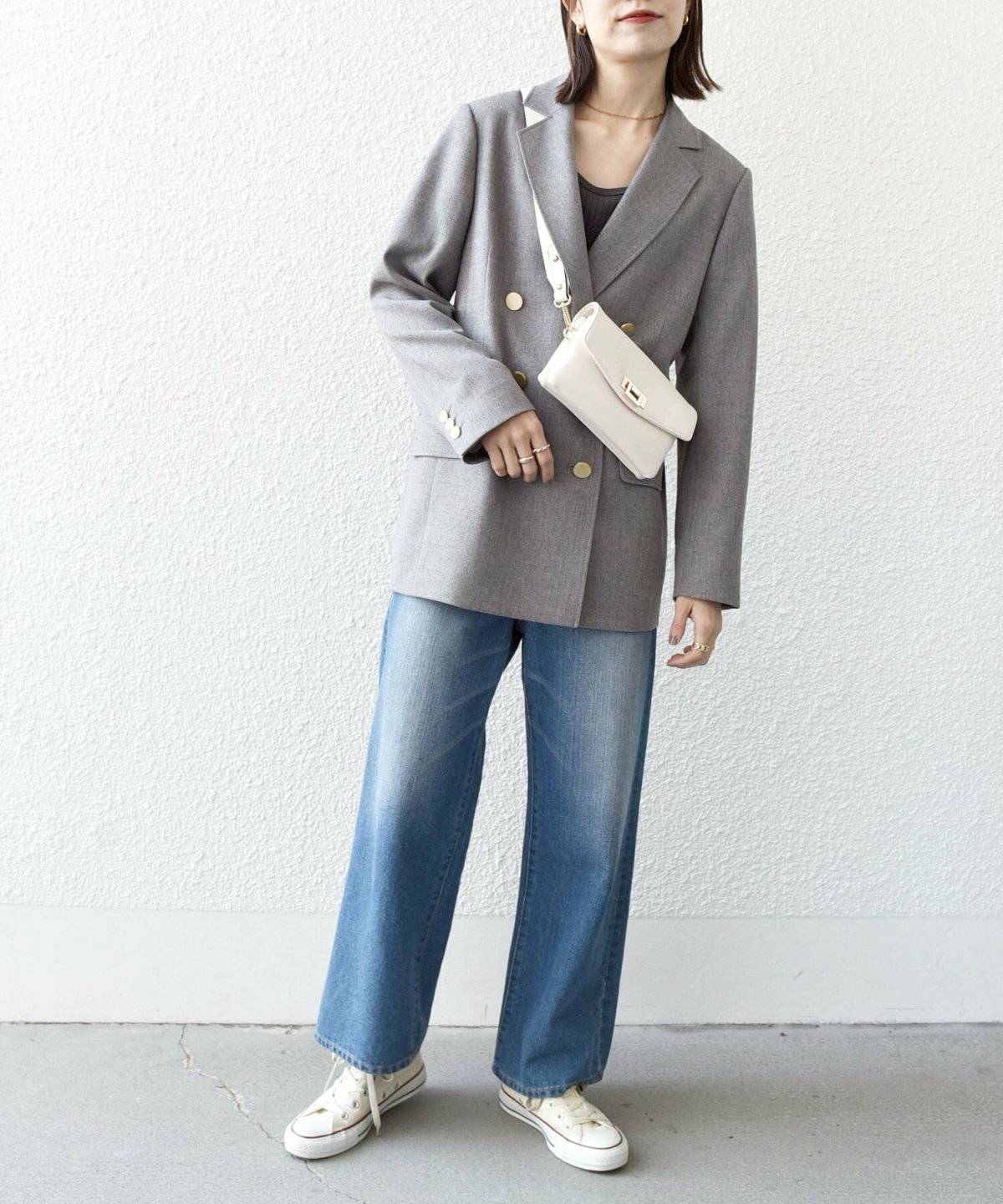 グレーのジャケットを羽織ってデニムを合わせた女性