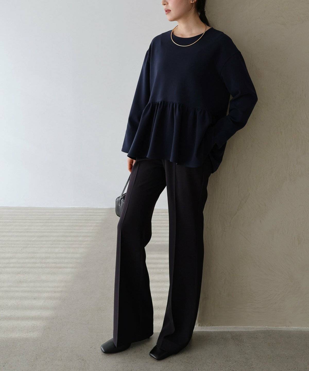 ネイビーのブラウスに黒パンツを合わせた女性