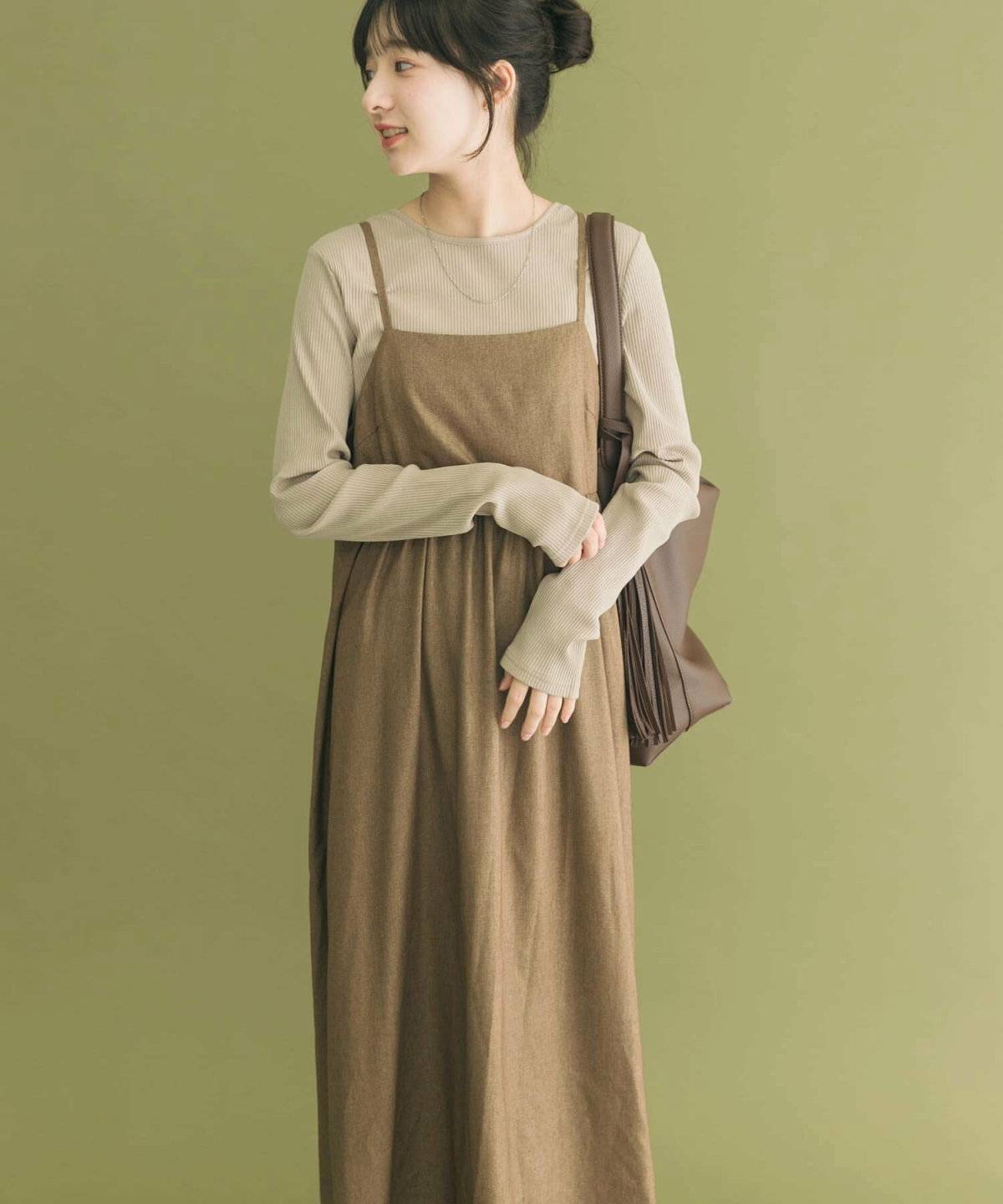 ベージュのトップスにブラウンのワンピースを重ねた女性