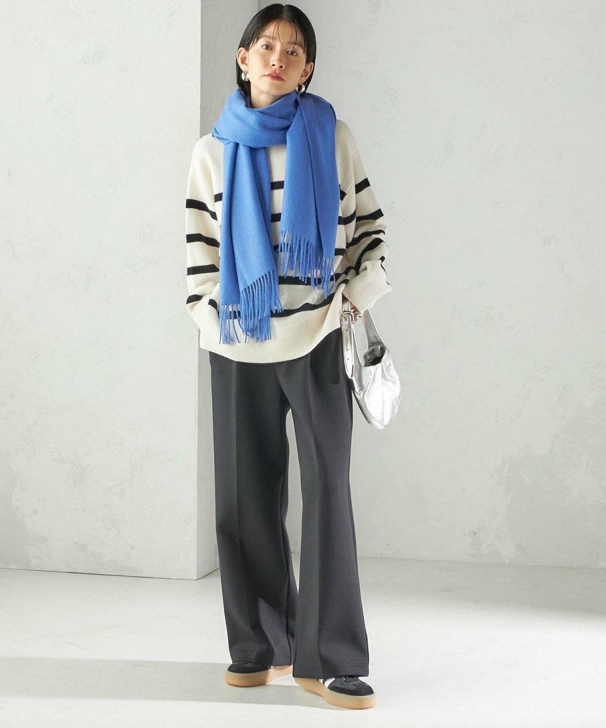 モノトーンコーデにブルーのマフラーを巻いた女性