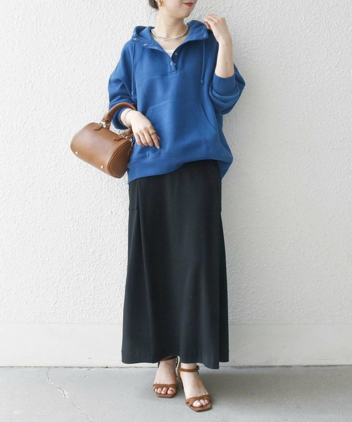 ブルーのパーカーに黒スカートを合わせた女性