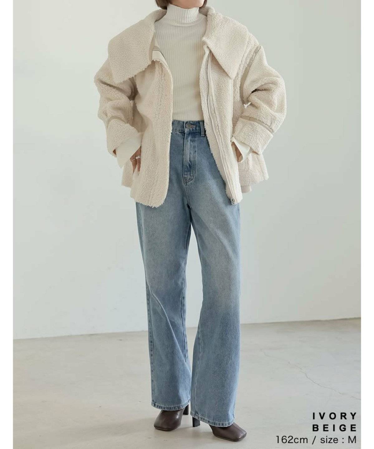 白ニットに白コートを合わせてデニムを穿いた女性