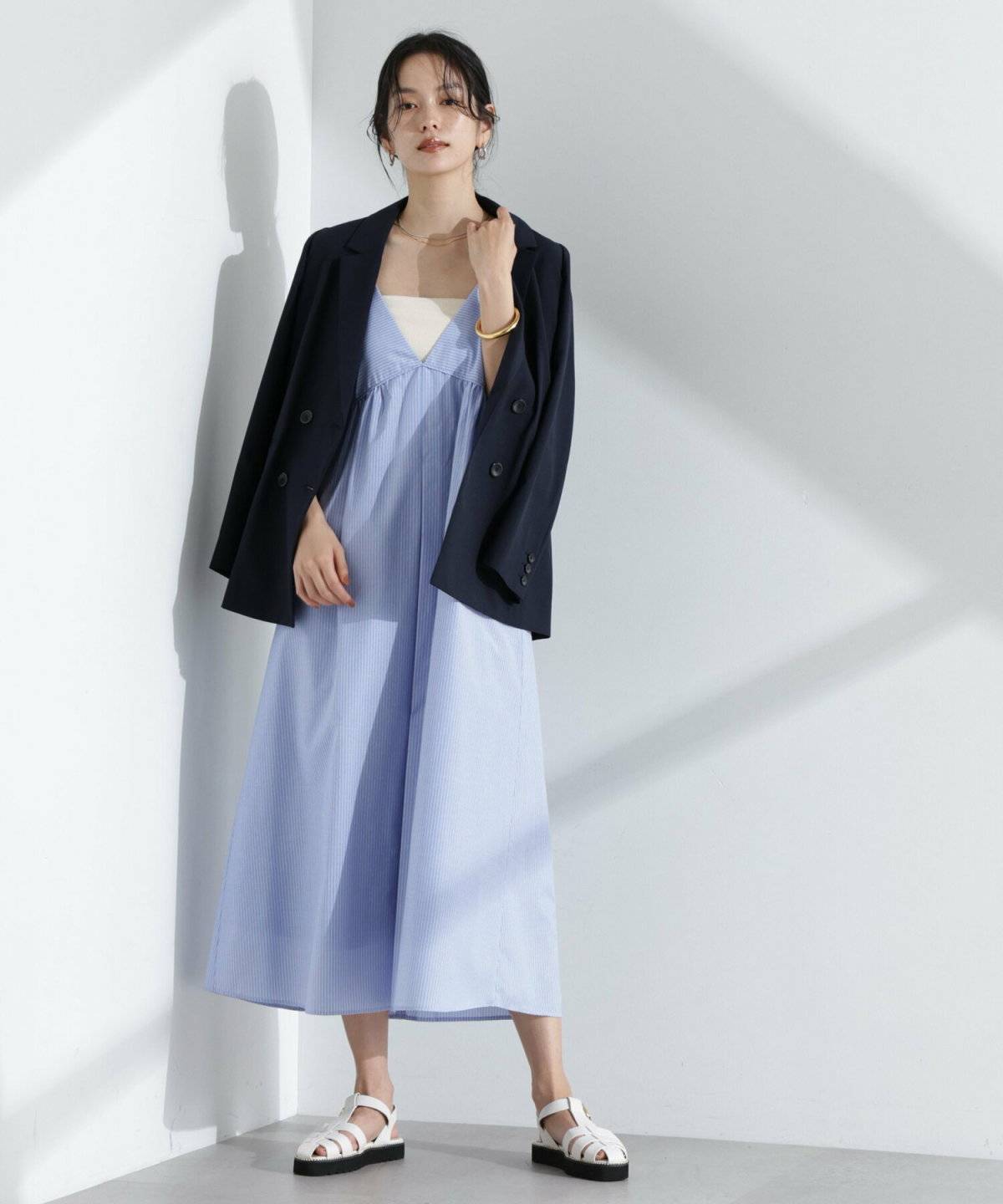 ブルーのワンピースにアウターを肩掛けした女性