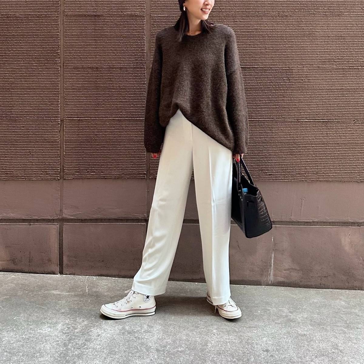 ブラウンのトップスに白パンツを合わせた女性