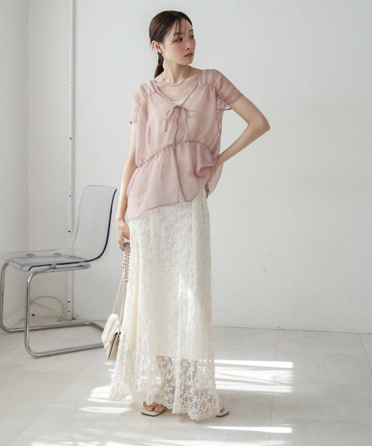 ピンクのブラウスにホワイトのスカートを合わせた女性