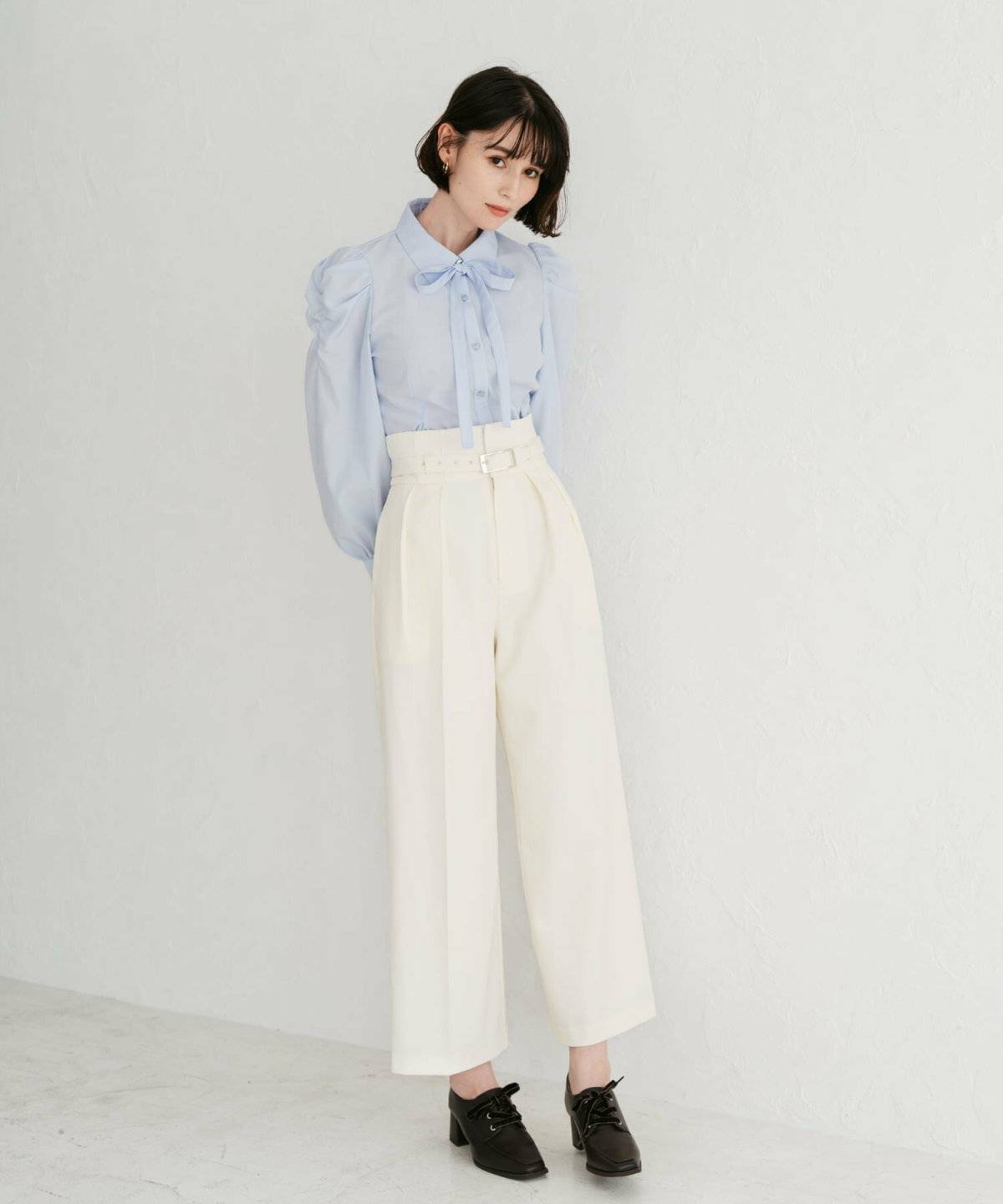 ブルーのブラウスにベージュのパンツを合わせた女性