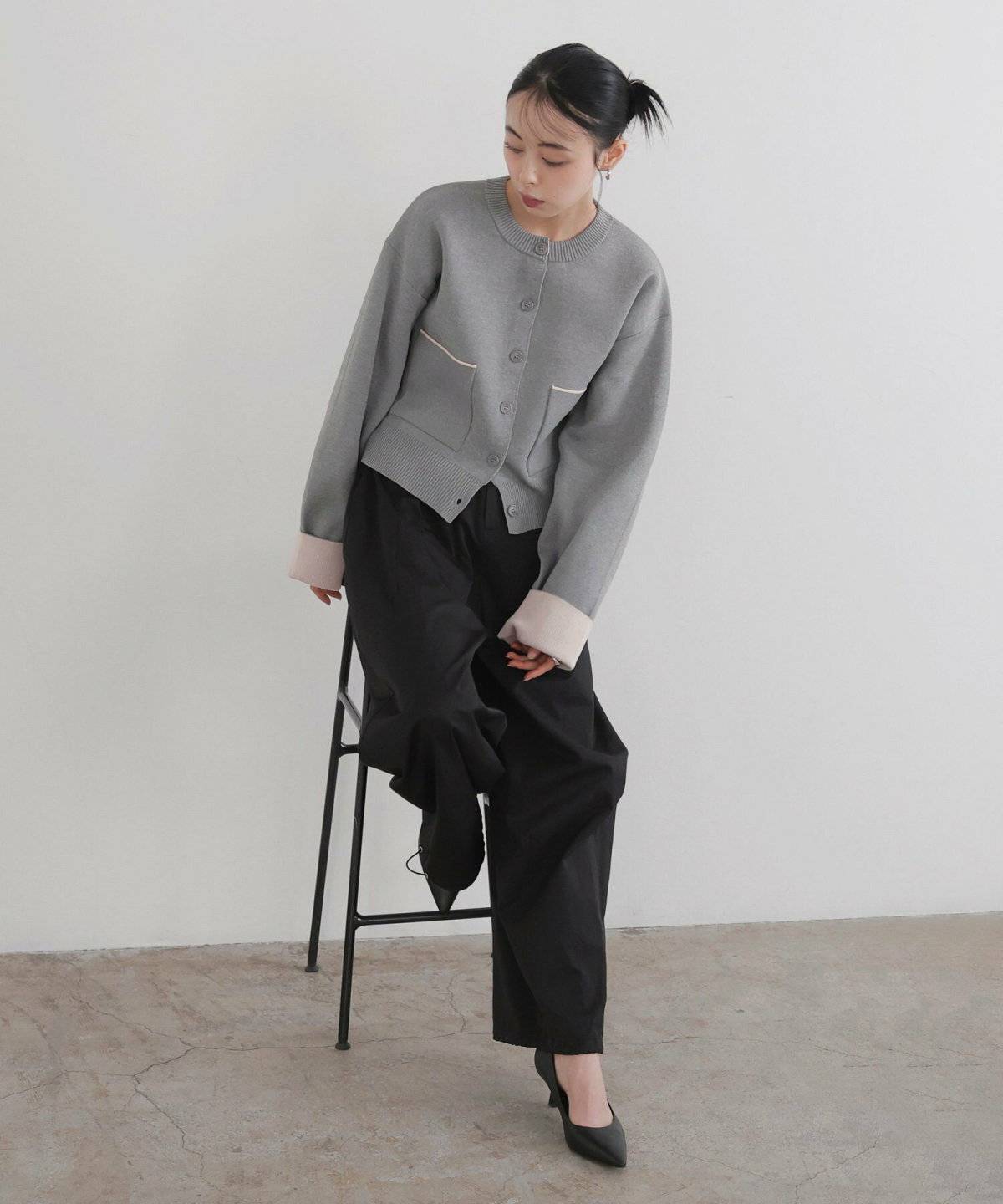 カーディガンを羽織って黒パンツを合わせた女性