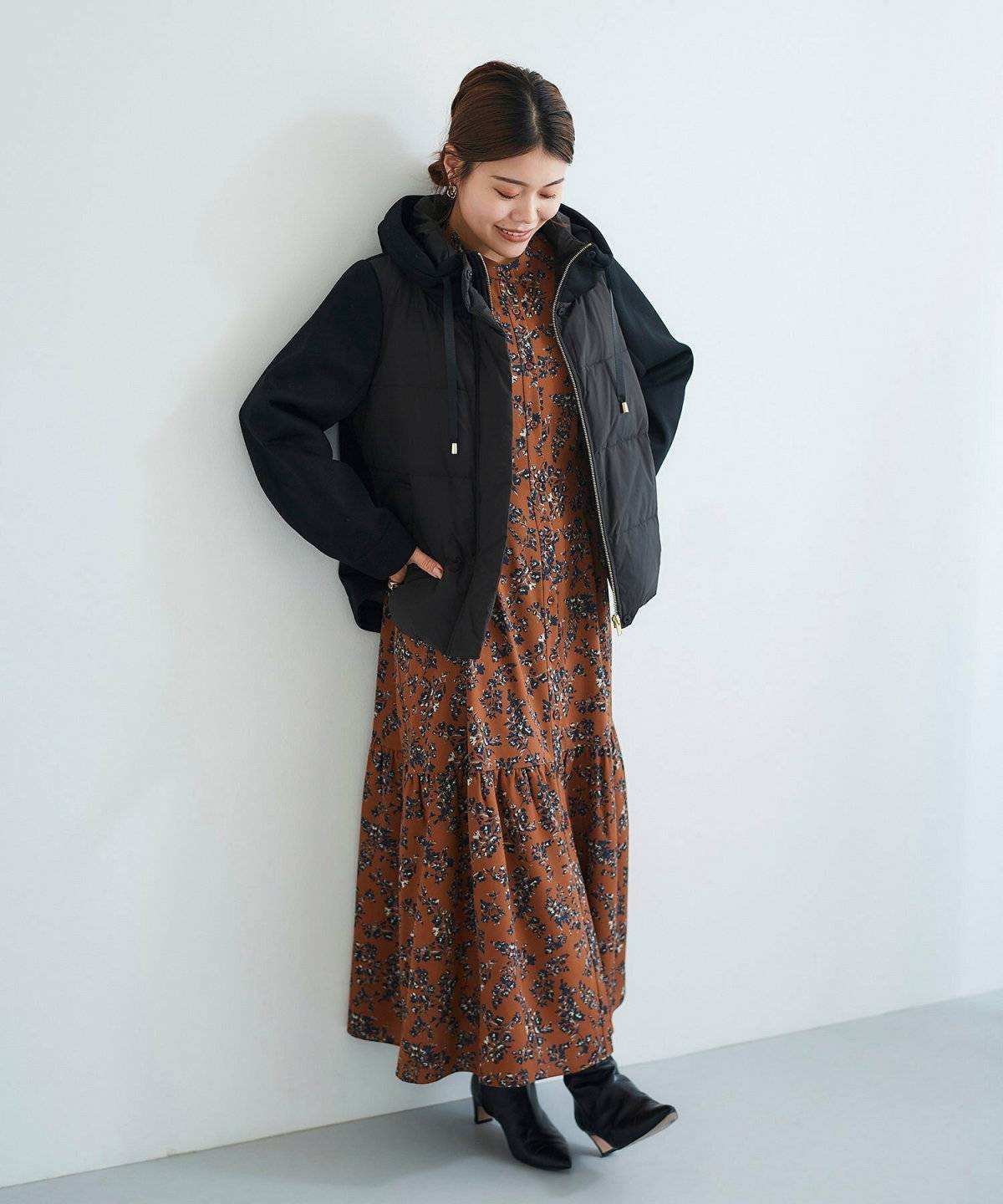 ブラウンワンピースに黒コートを羽織った女性