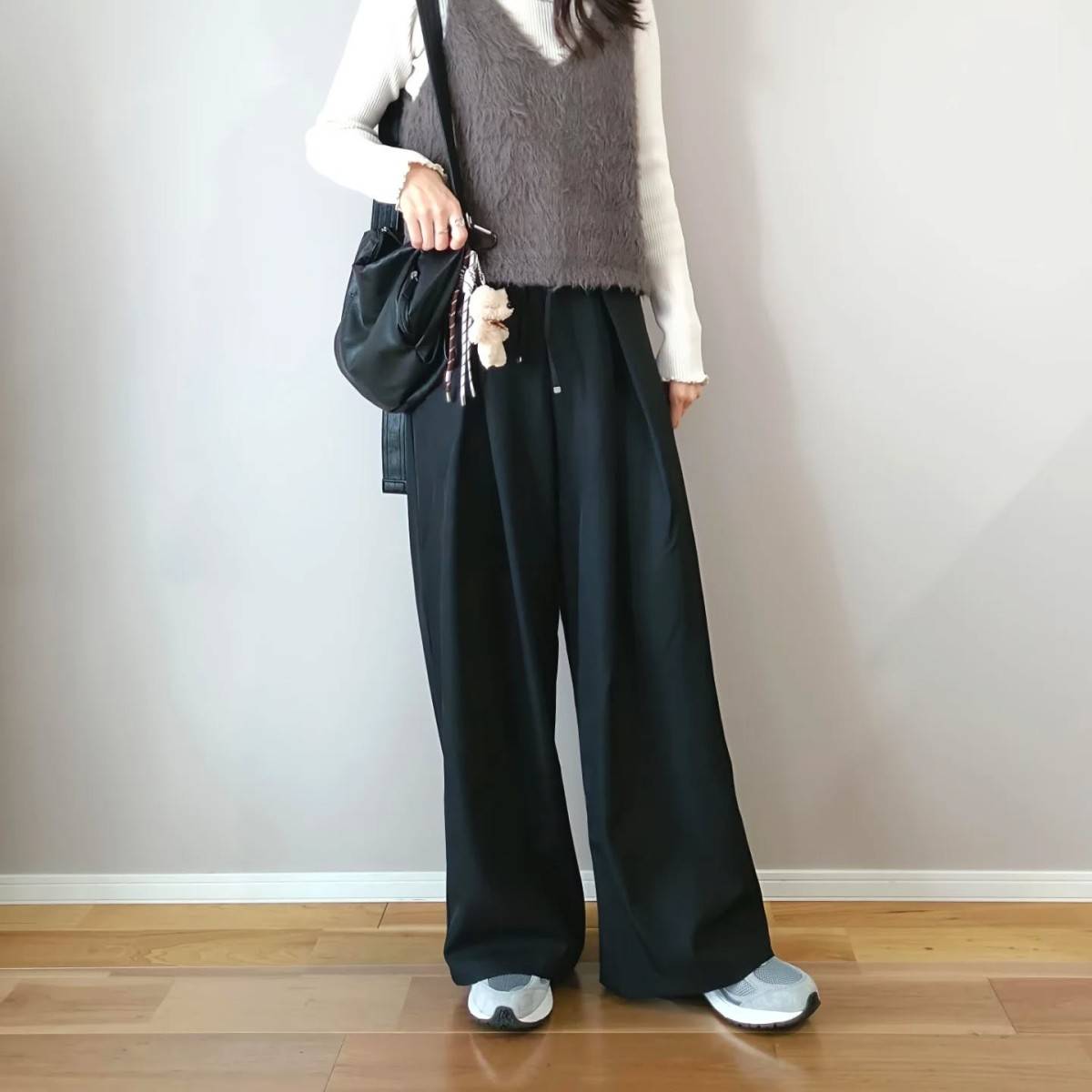 グレーのベストに黒パンツを合わせた女性