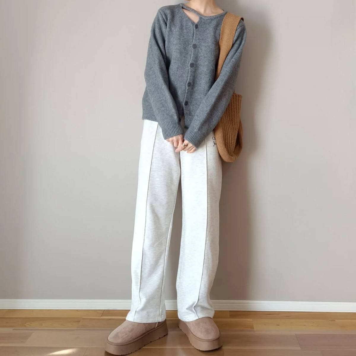 グレーのカーディガンに白パンツを合わせた女性