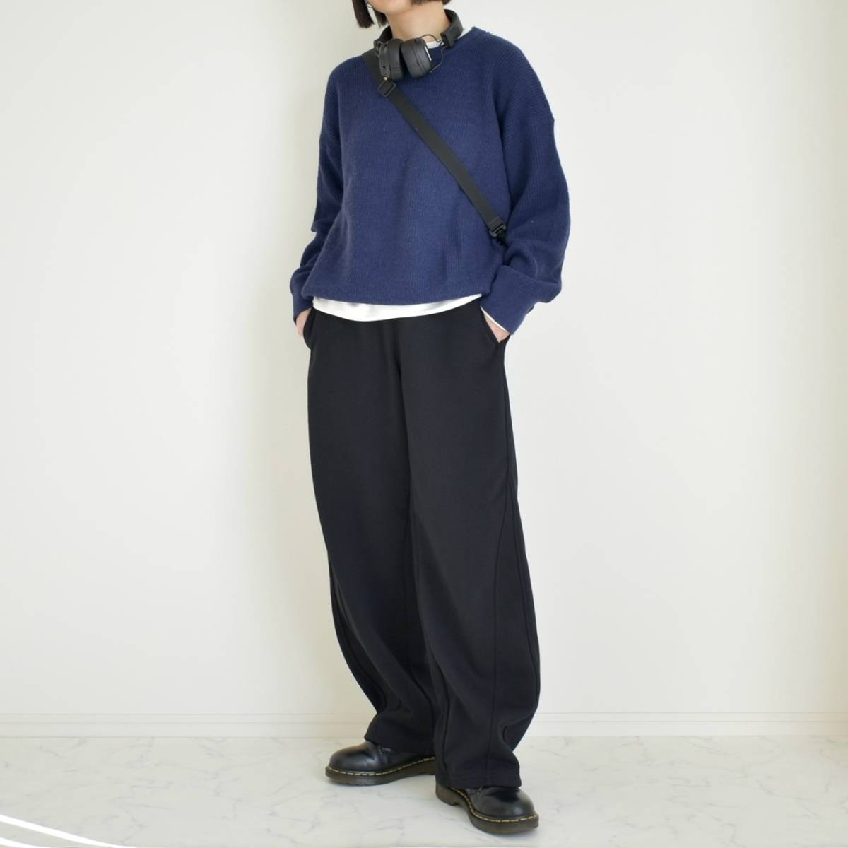 ネイビーのニットに黒パンツを合わせた女性