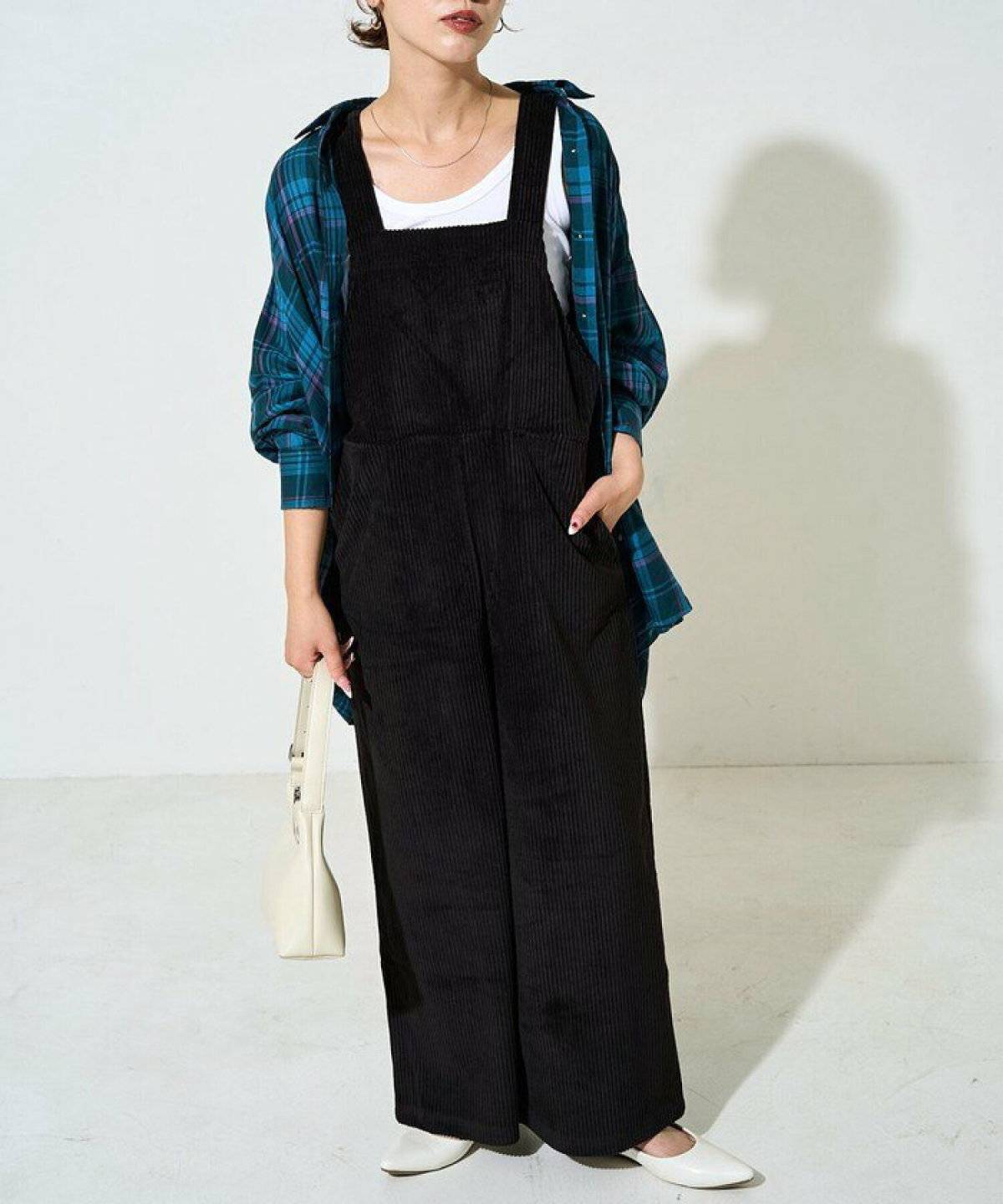 黒サロペットの上にチェック柄シャツを羽織った女性