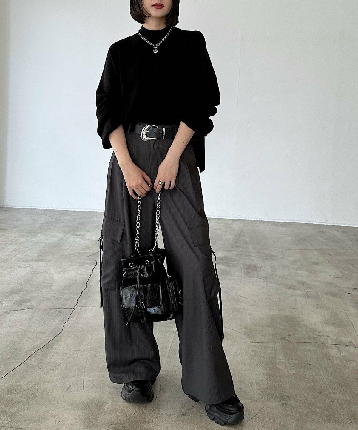 黒トップスにグレーパンツを合わせた女性