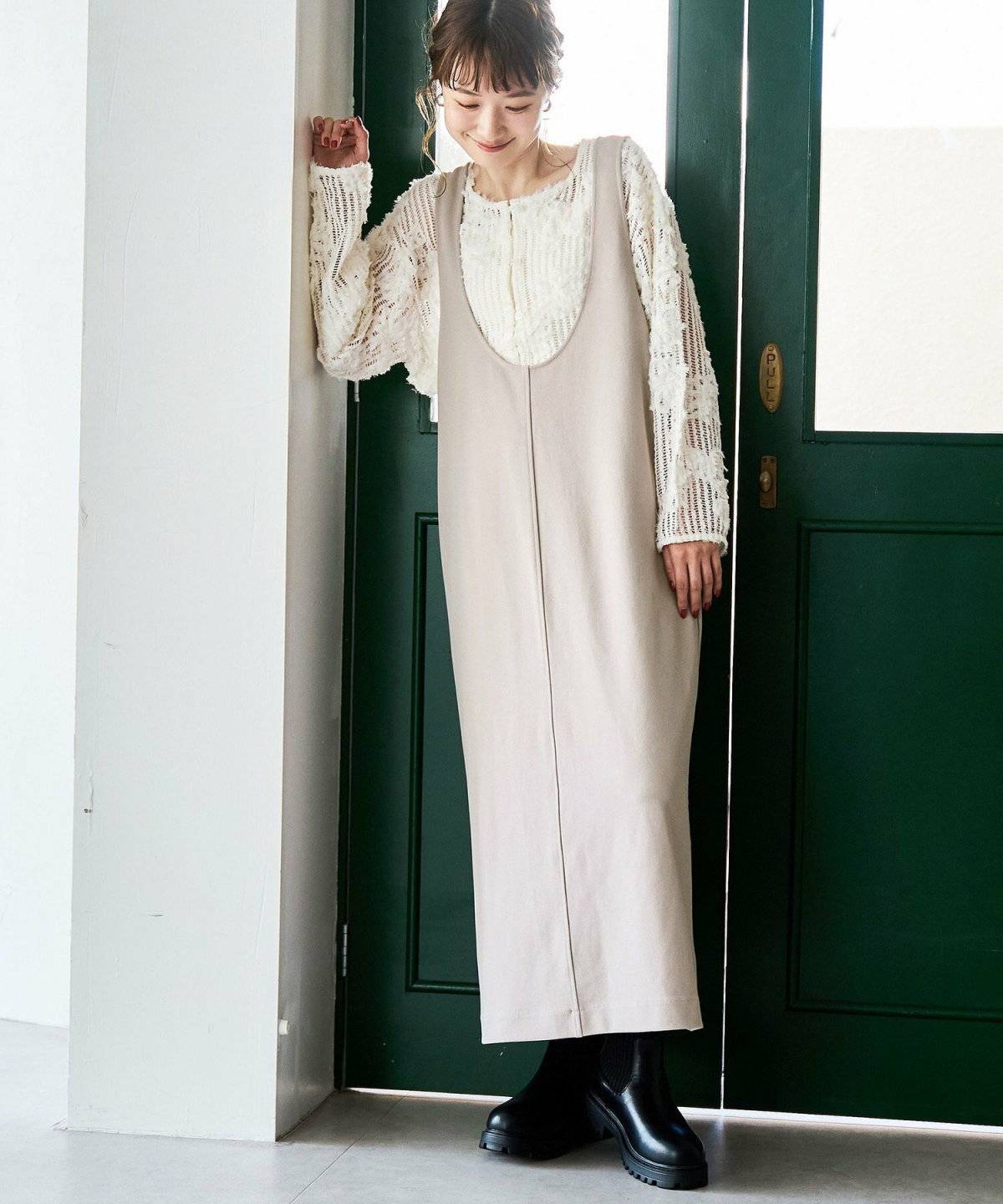 白トップスにベージュのジャンパースカートを合わせた女性