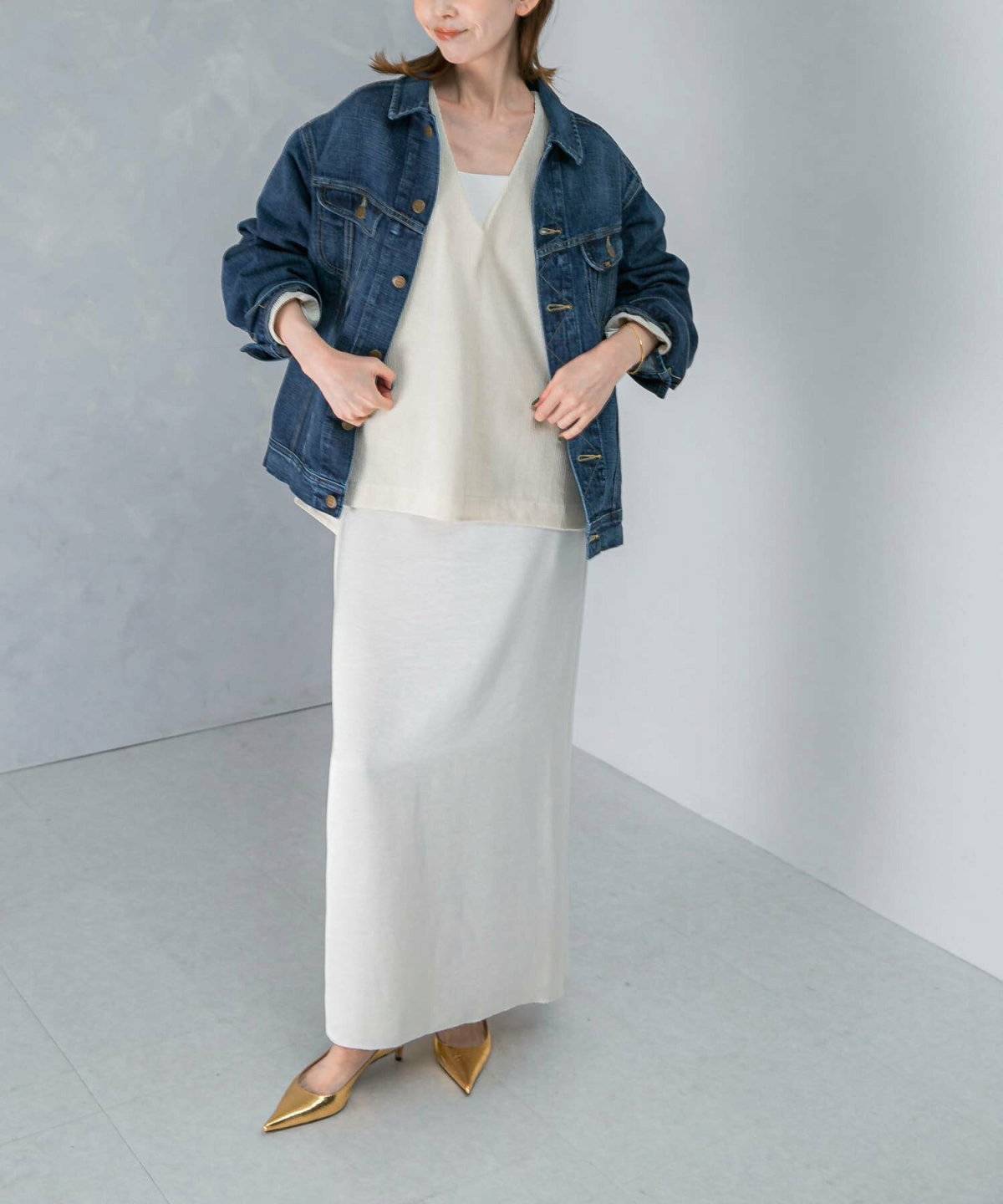 ホワイトコーデにデニムジャケットを肩掛けした女性
