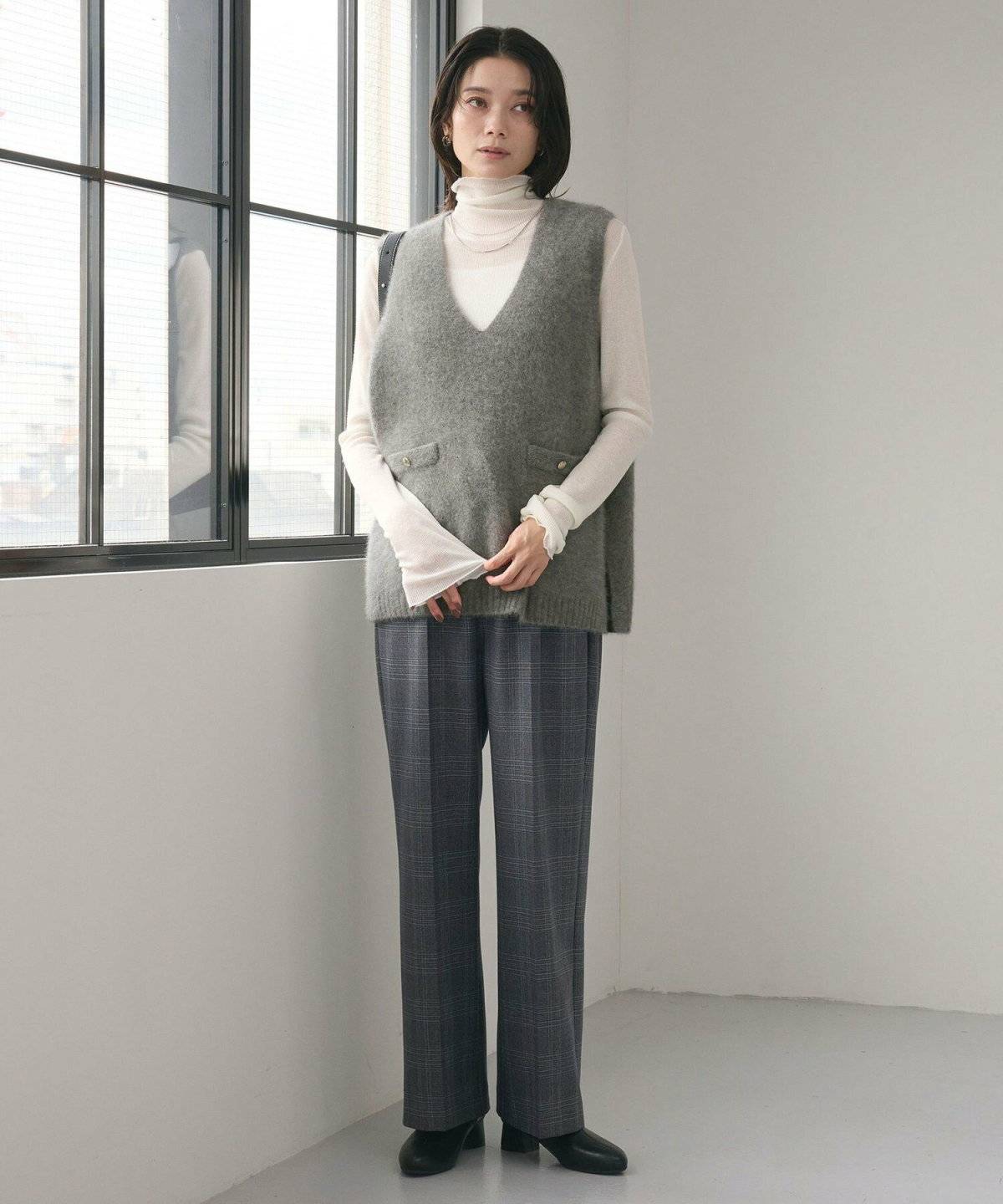 ハイネックトップスにベストを重ねた女性