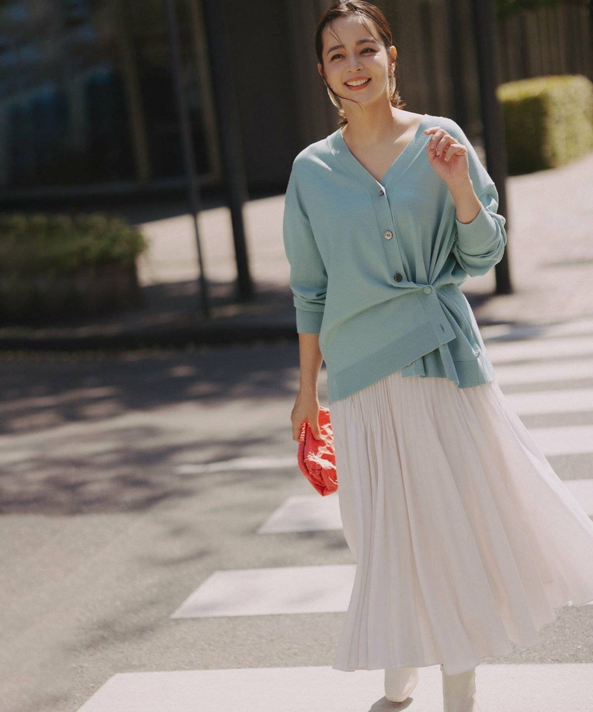 グリーンのカーディガンに白スカートを合わせた女性