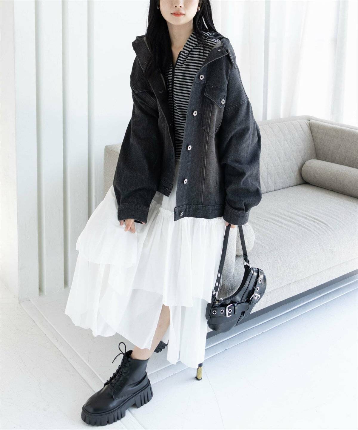 ボーダー柄トップスにデニムシャツを羽織って白スカートを合わせた女性