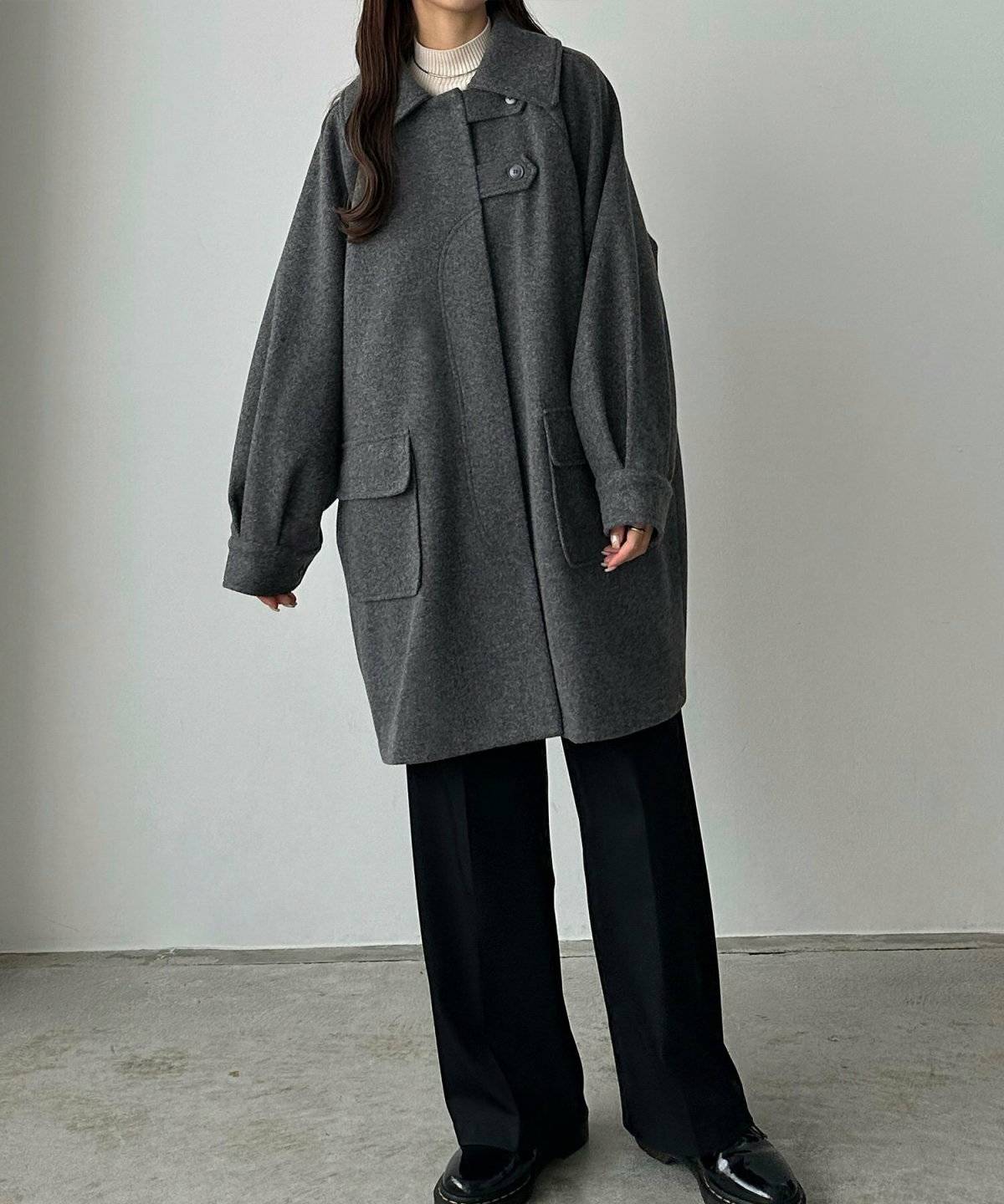 グレーのアウターに黒パンツを合わせた女性