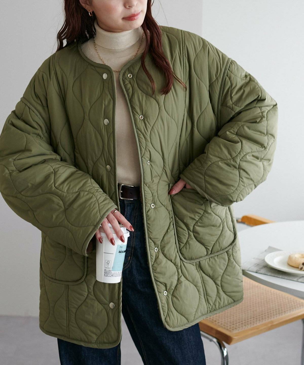 グリーンの中綿コートにデニムを合わせた女性