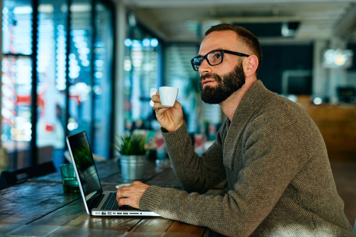 仕事しながらコーヒーを飲む男性