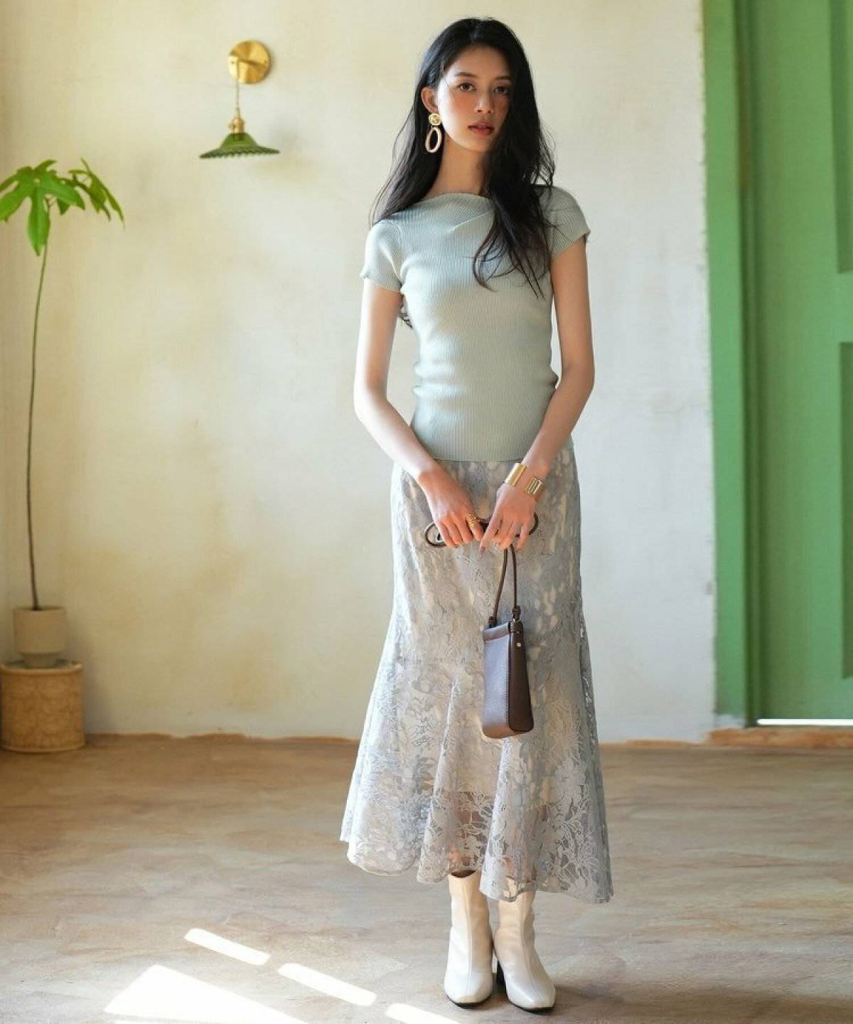 グリーンのトップスにホワイトのスカートを合わせた女性