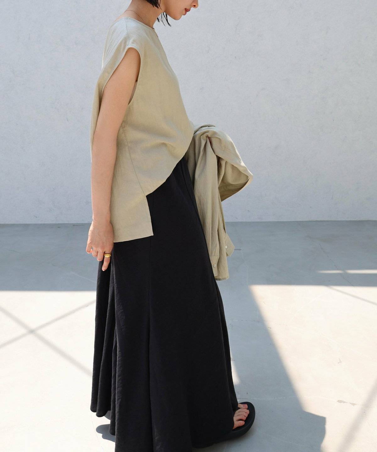 ベージュのトップスに黒スカートを合わせた女性