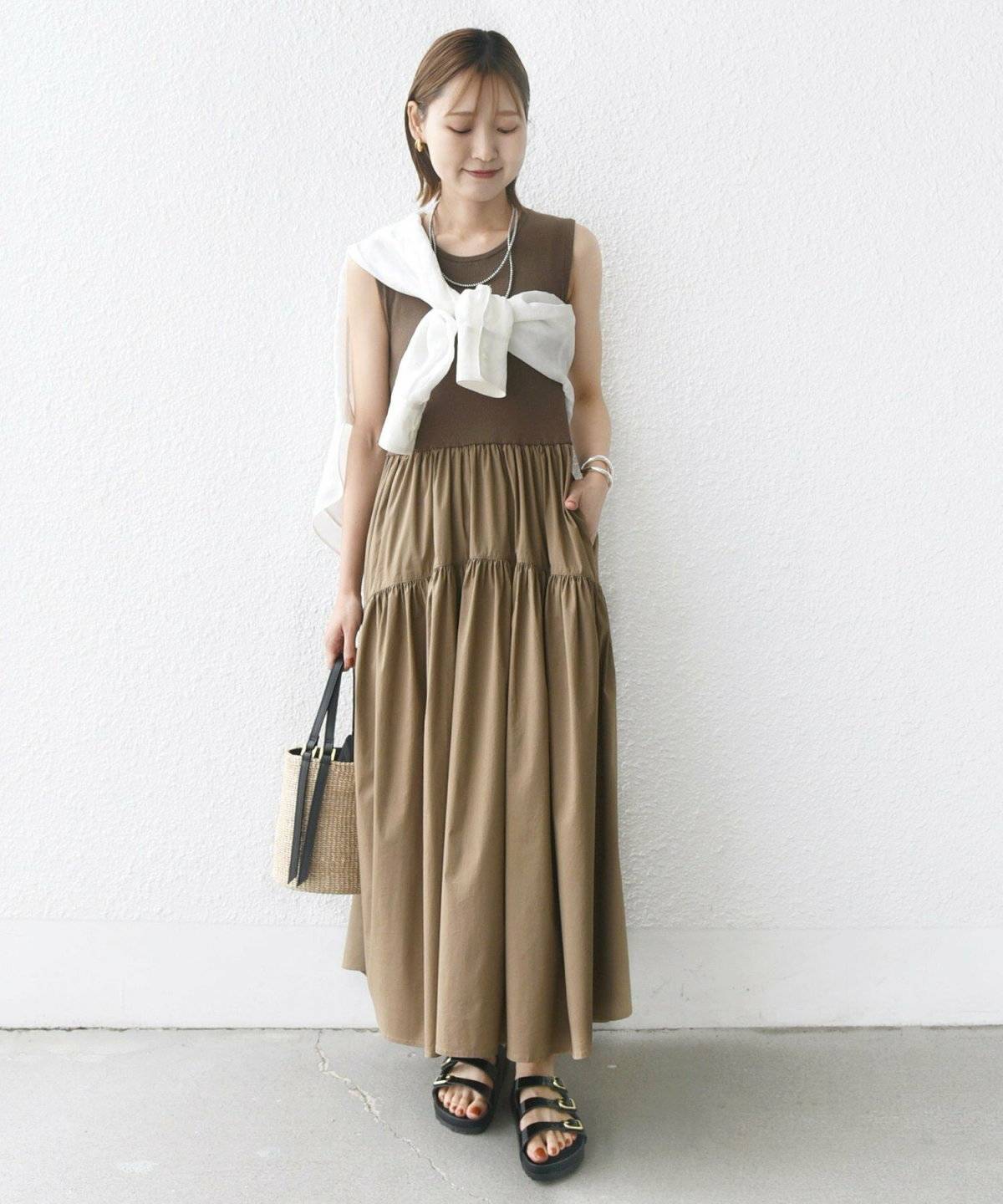 ブラウンのワンピースにホワイトのシャツをたすき掛けした女性