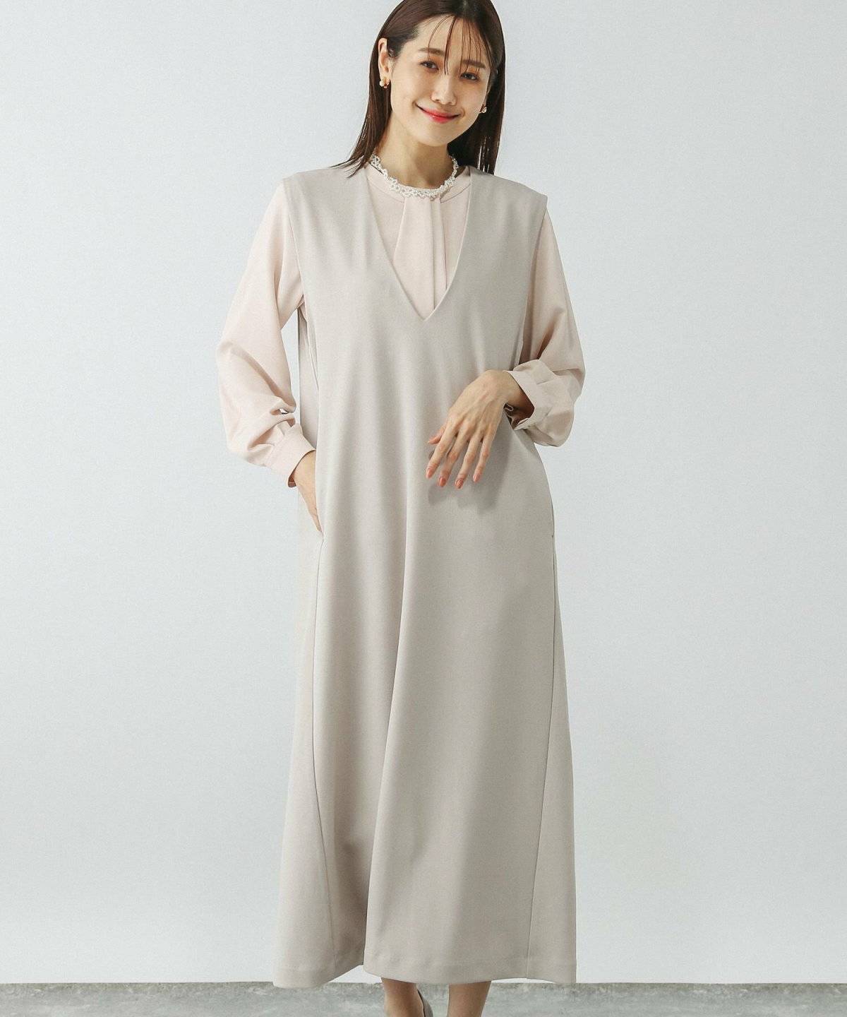 グレーのワンピースにピンクのブラウスを合わせた女性