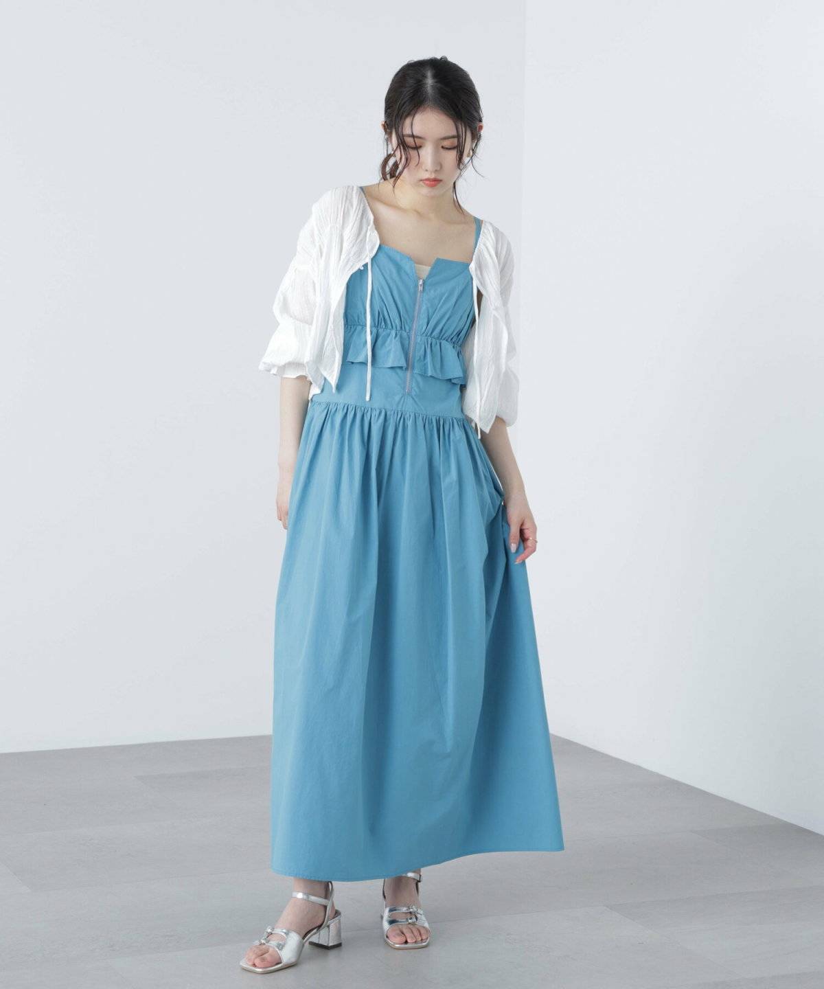 ブルーのワンピースにホワイトのブラウスを重ねた女性