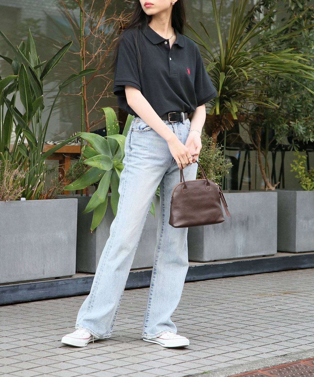 黒のポロシャツにデニムを合わせた女性