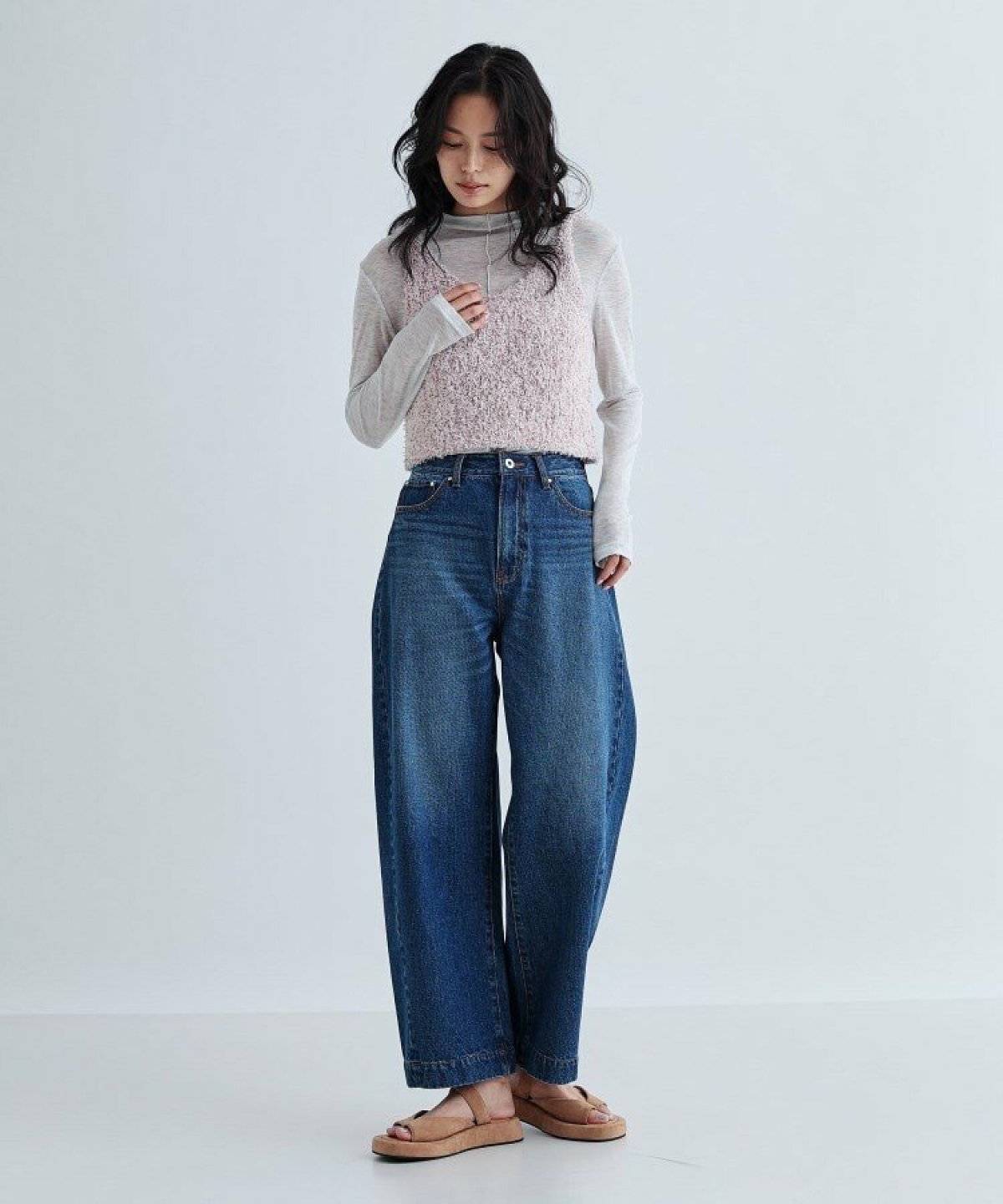 トップスにピンクのベストを重ねてデニムを合わせた女性