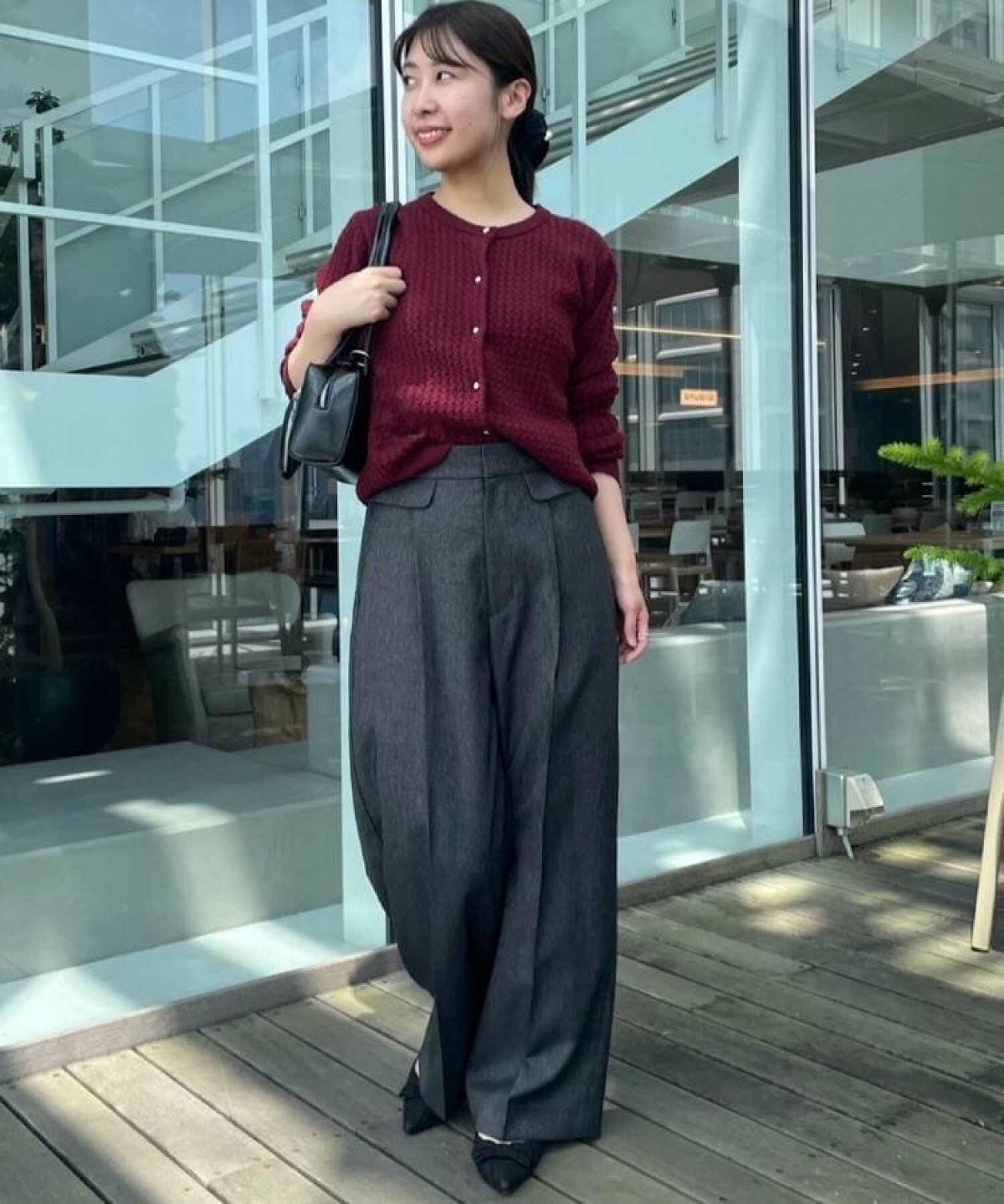 カーディガンに黒パンツを合わせた女性