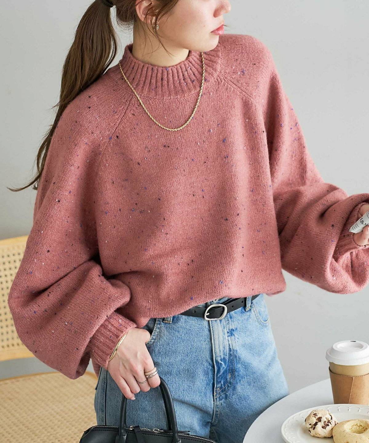 ピンクのニットにデニムを合わせた女性