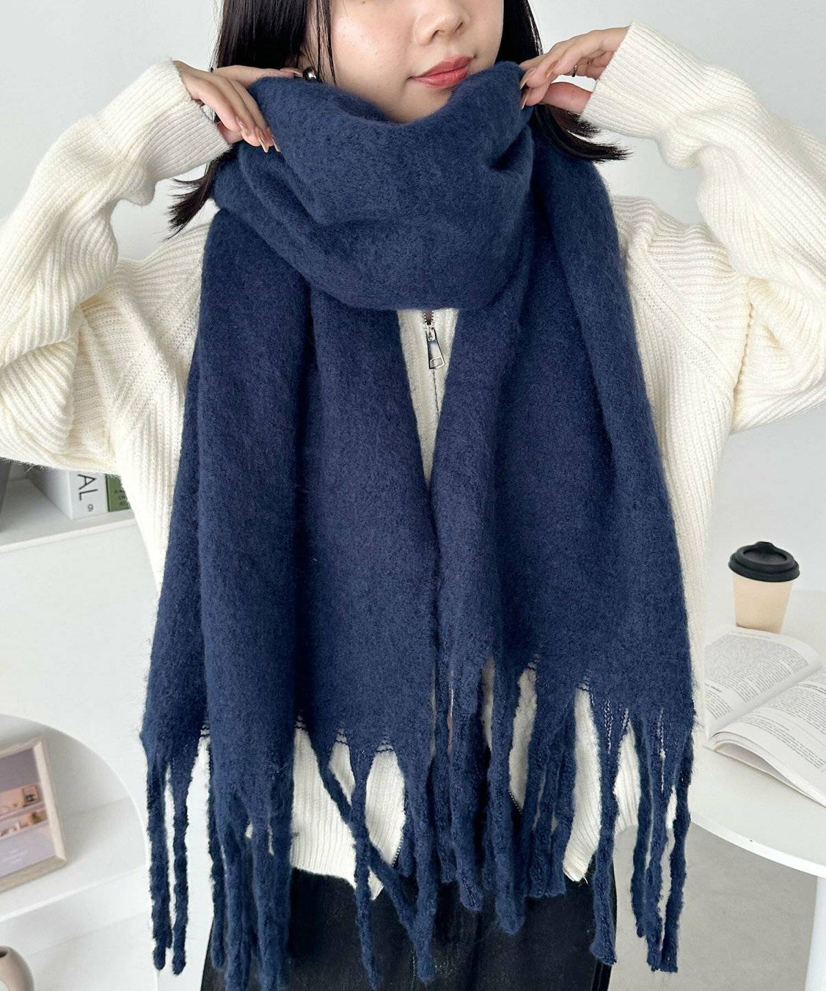 モノトーンコーデにブルーのマフラーを巻いた女性