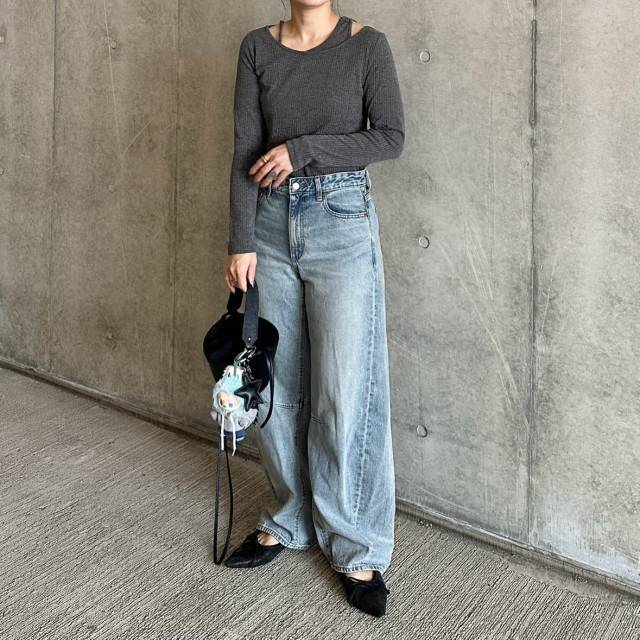 グレーのトップスにデニムパンツを合わせた女性