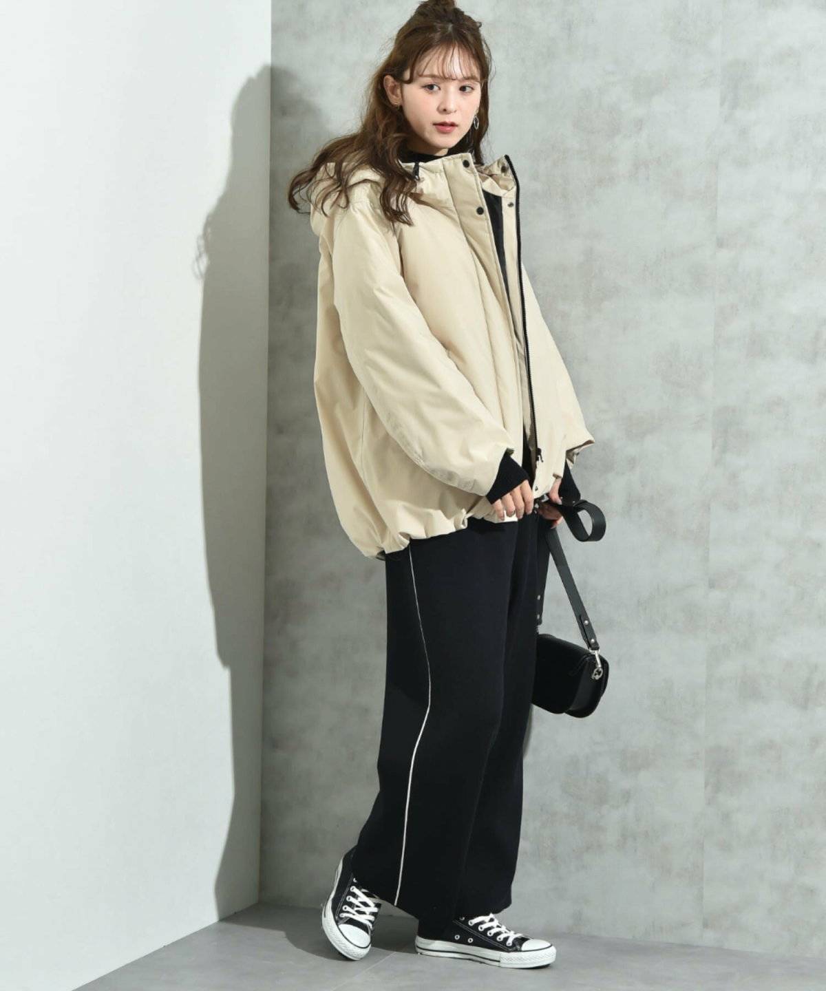 ブラックコーデにベージュのダウンを合わせた女性