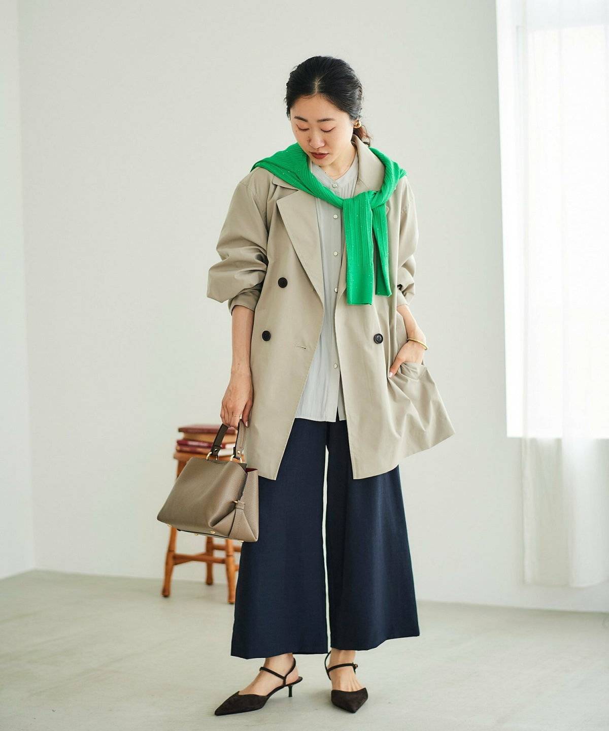 ベージュのトレンチコートに黒パンツを合わせた女性