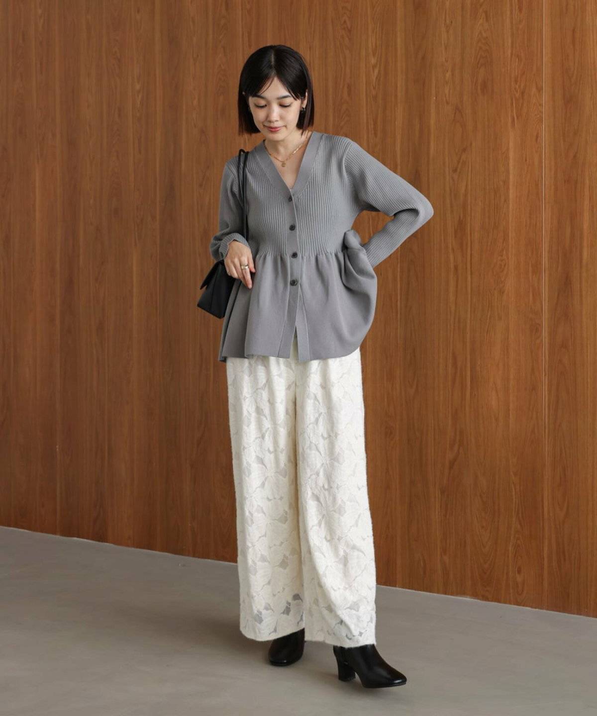 グレーのニットに白パンツを合わせた女性