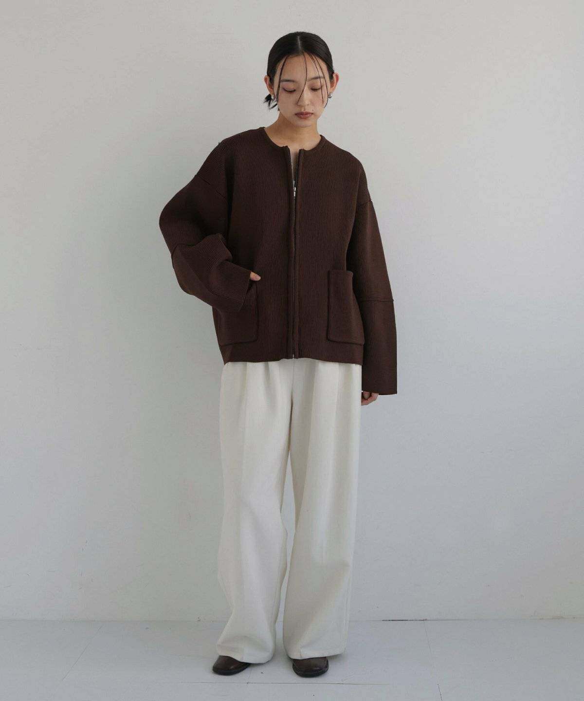 ブラウンカーディガンに白パンツを合わせた女性