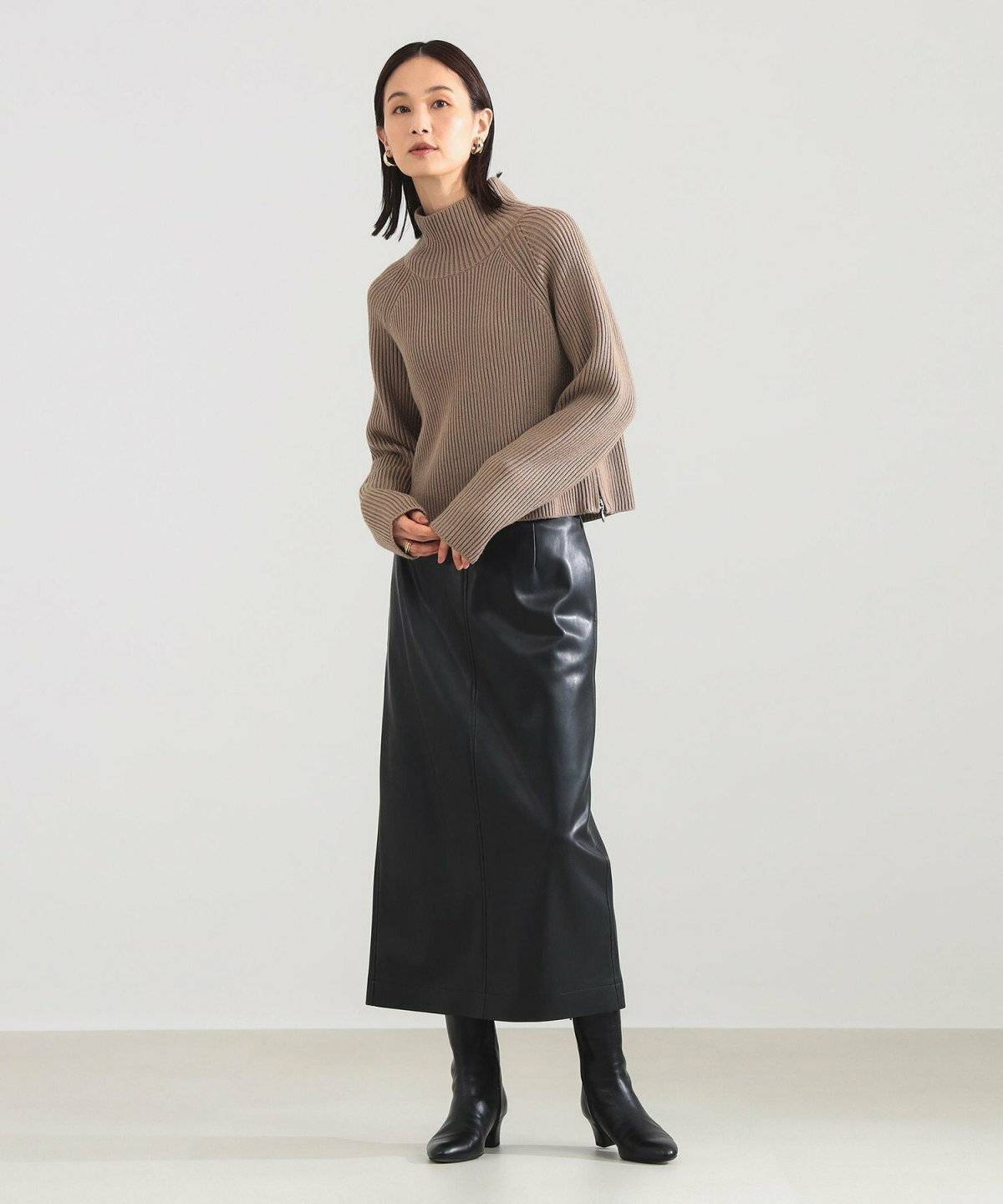 ベージュのカーディガンに黒スカートを合わせた女性