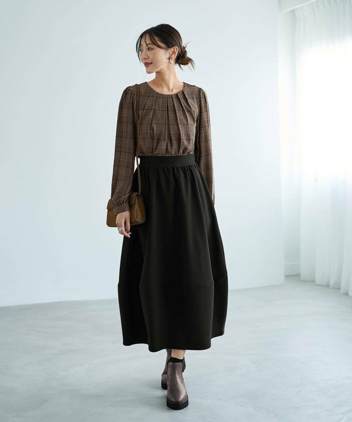 チェック柄ブラウスに黒スカートを合わせた女性
