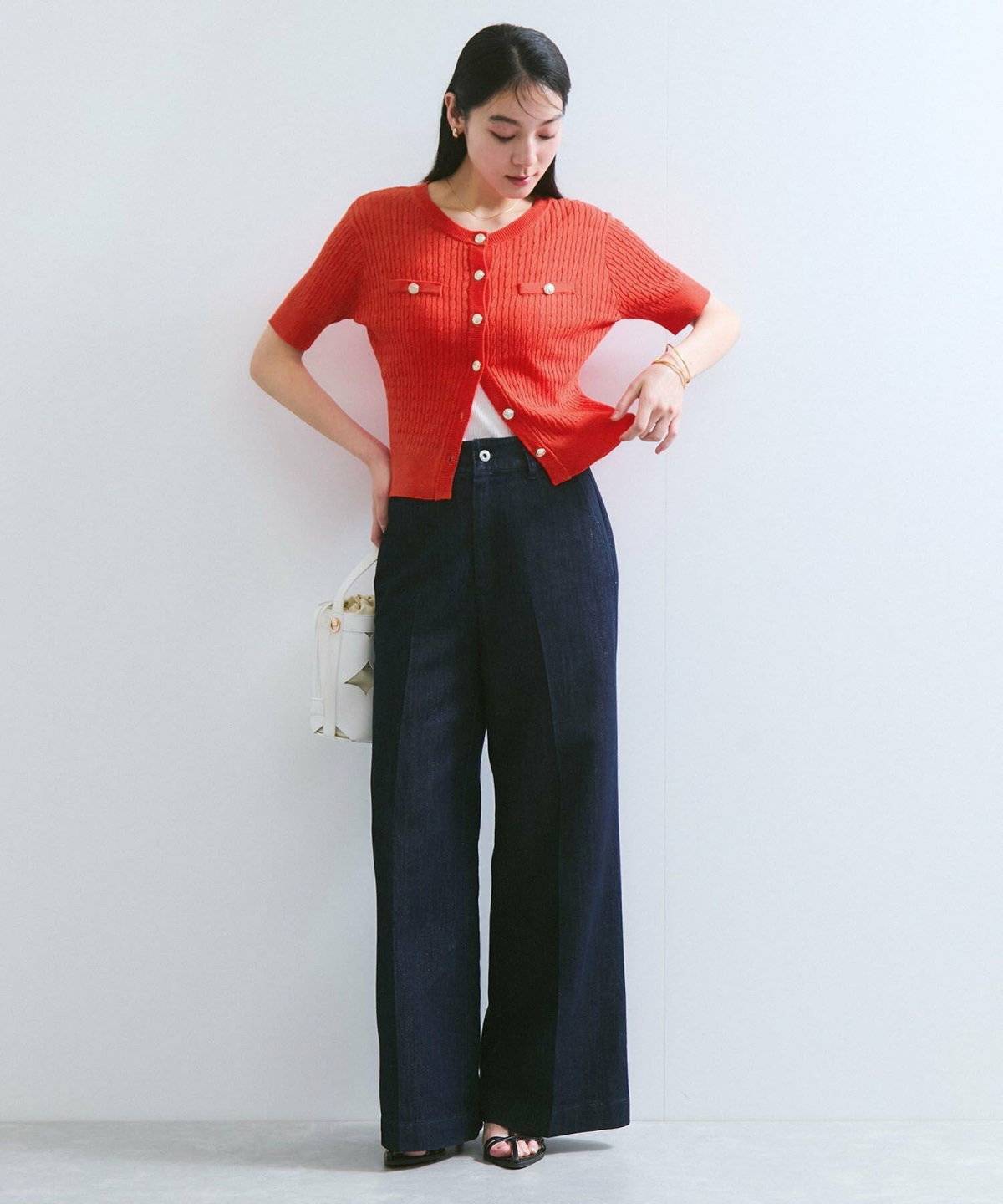 赤カーディガンにパンツを合わせた女性