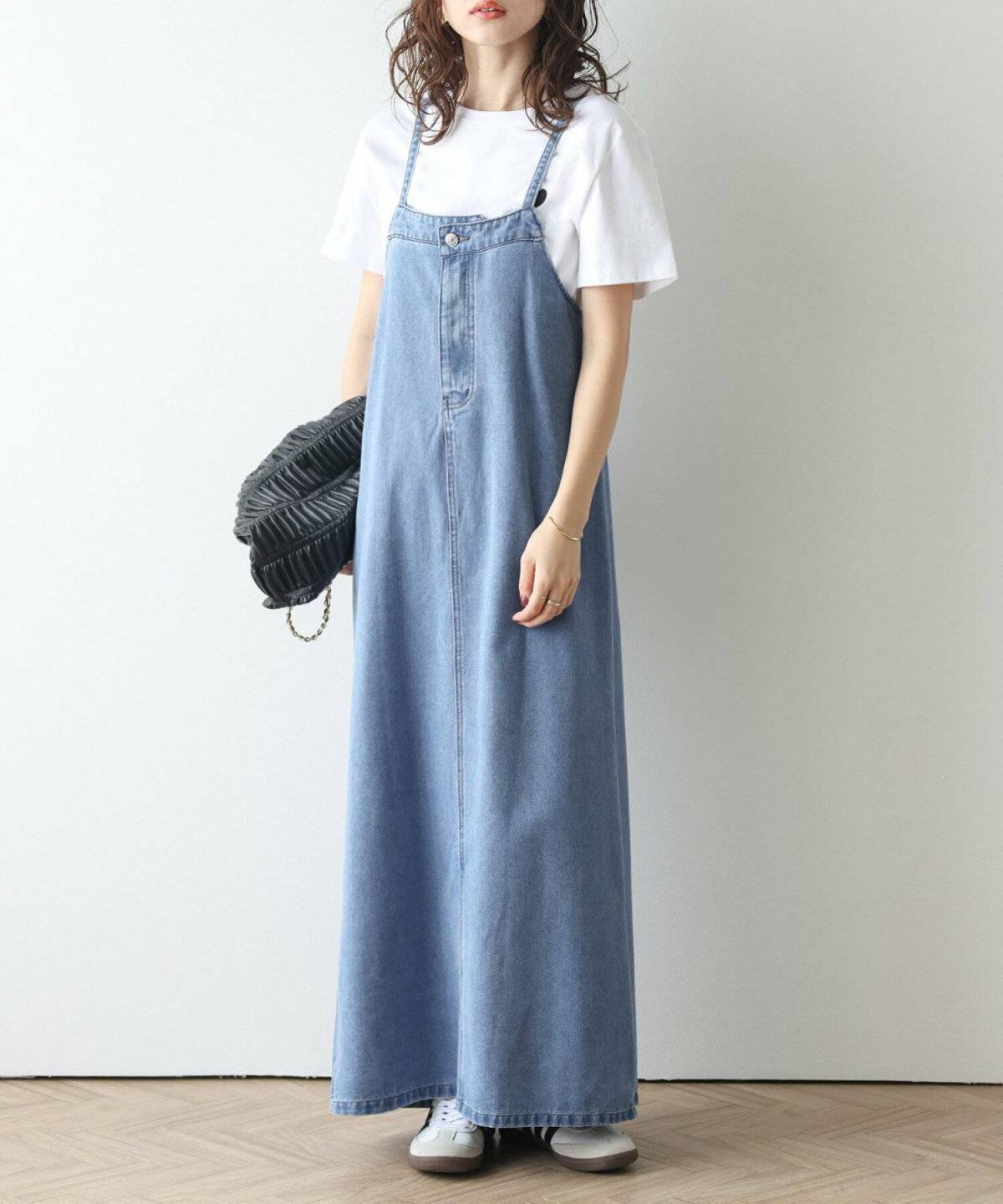 白トップスにデニムワンピースを合わせた女性