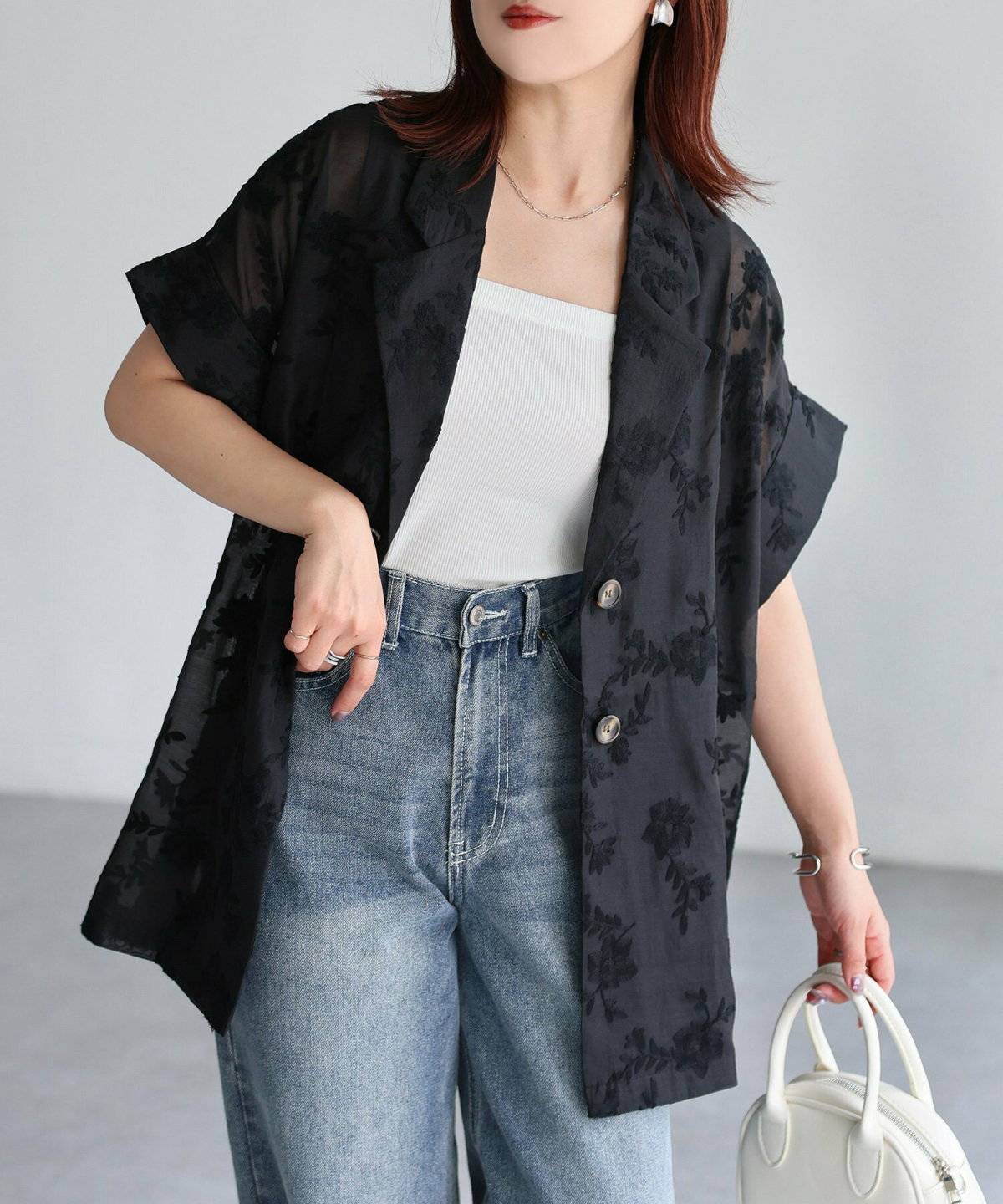 白トップスにネイビーのジャケットを羽織ってデニムを穿いた女性