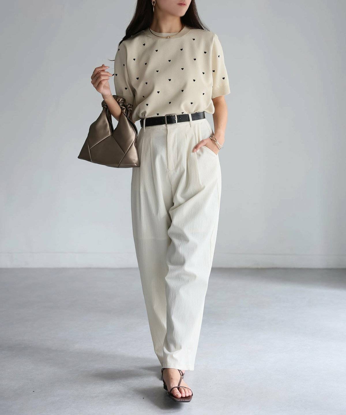 ベージュトップスに白パンツを合わせた女性