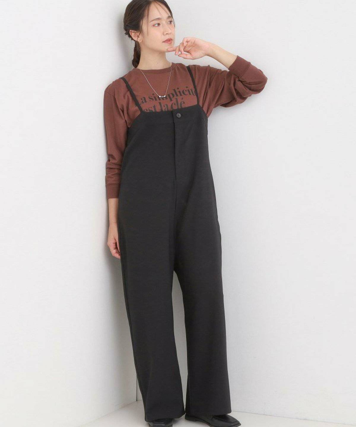 ブラウンのトップスに黒のサロペットを合わせた女性