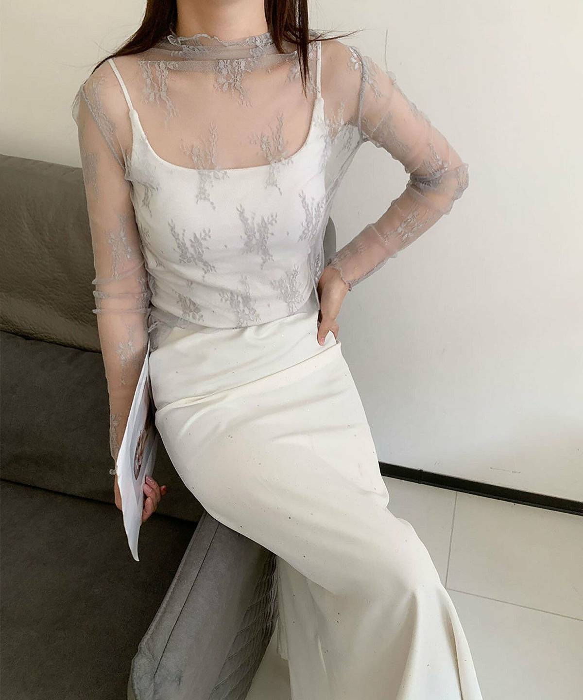グレーのシアートップスに白スカートを合わせた女性