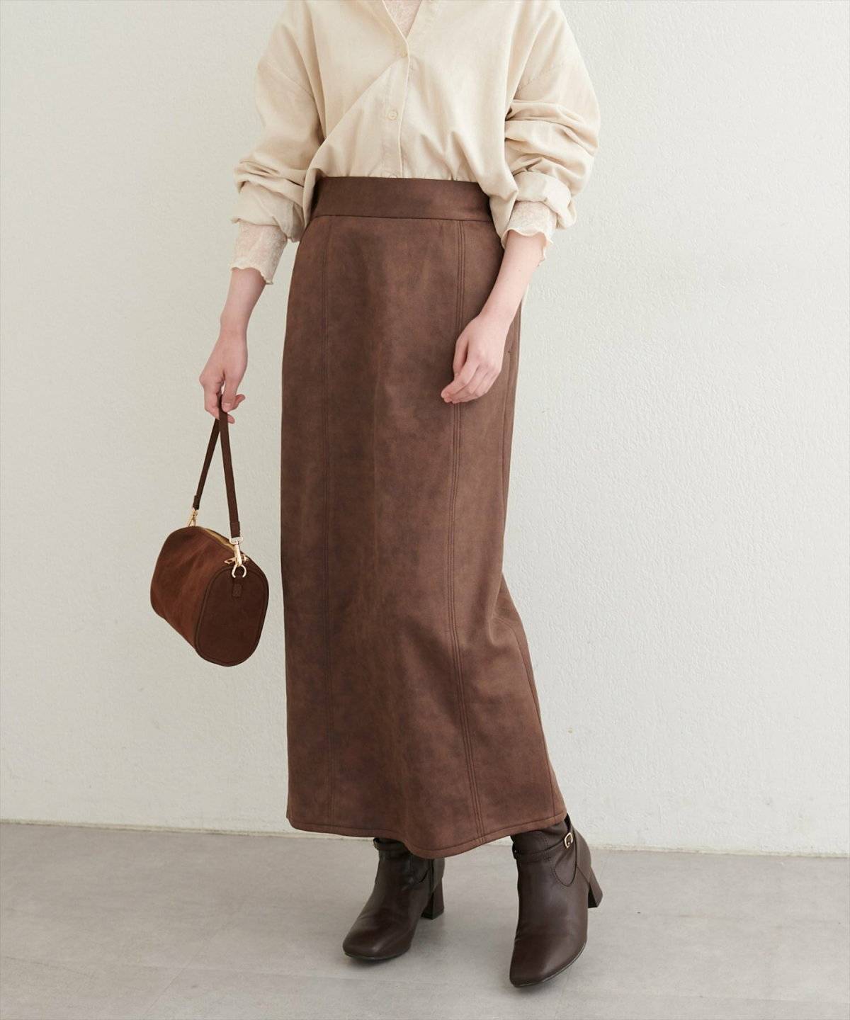 ベージュのブラウスにブラウンのスカートを合わせた女性