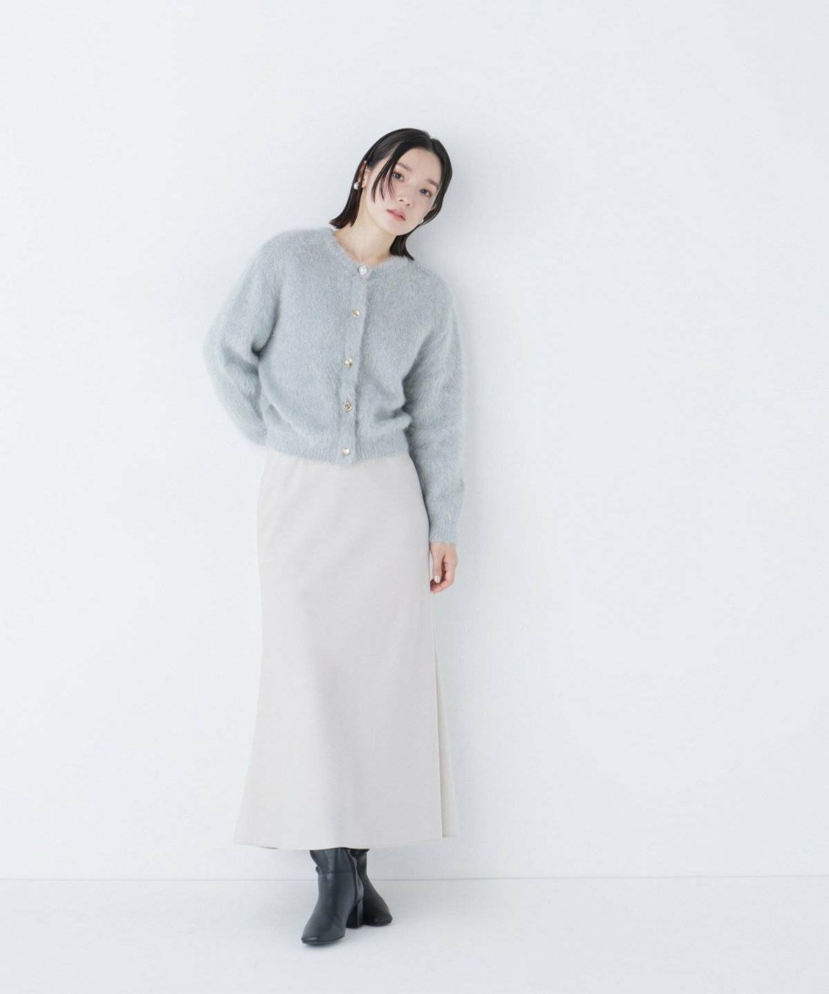 グリーンのニットに白スカートを合わせた女性